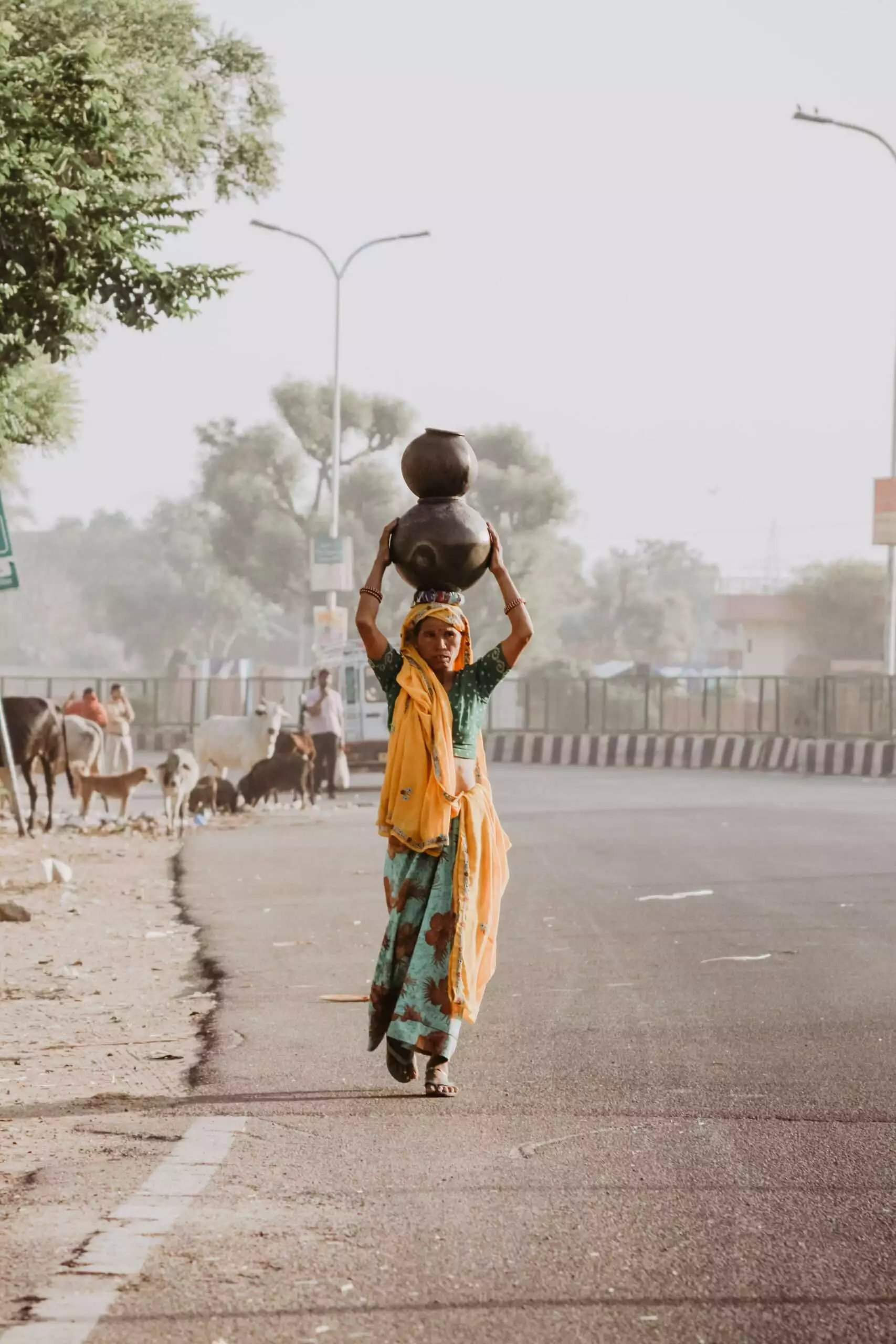 A lady carrying a pot on the road of India